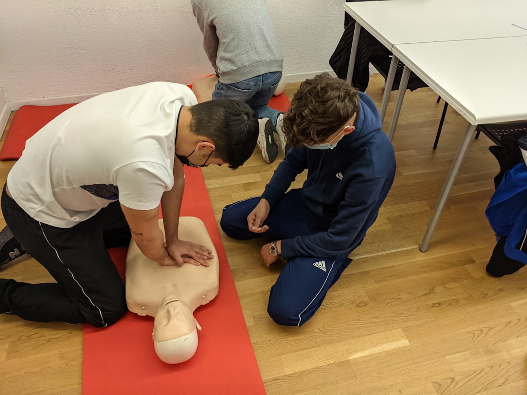 First aid at work training session with CPR practice on a mannequin in a UK workplace