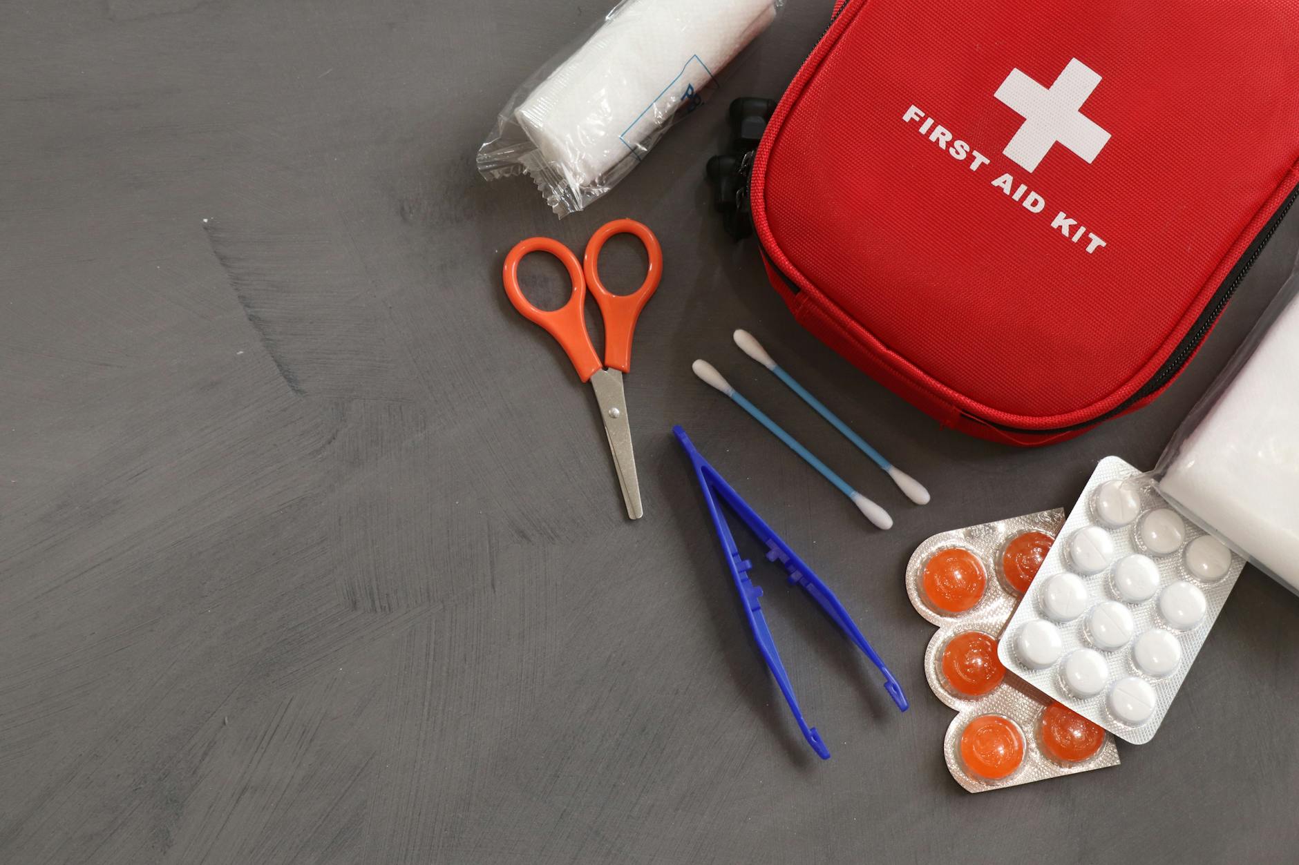 UK workplace first aid kit with essential medical supplies including bandages and scissors
