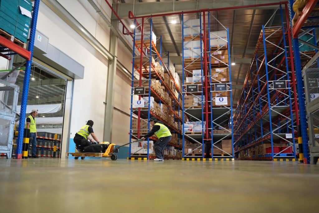 UK warehouse workers in high-visibility vests safely moving pallets and stock